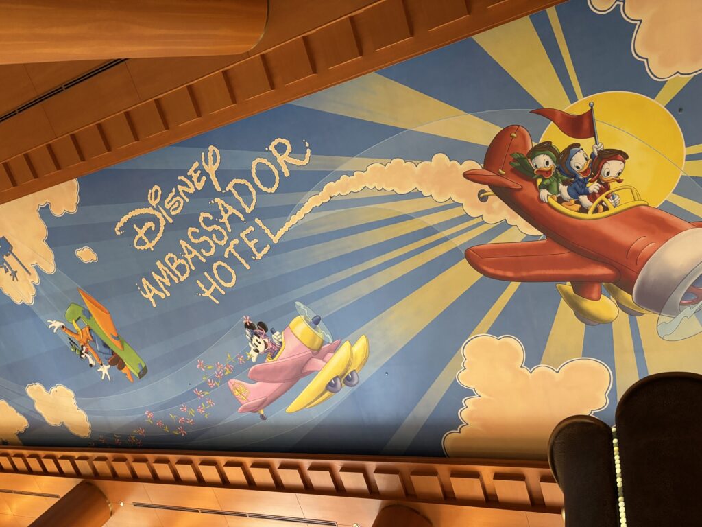 ディズニーアンバサダーホテルのロビー天井に描かれた、ディズニーキャラクターたちが飛行機で空を飛ぶカラフルな壁画