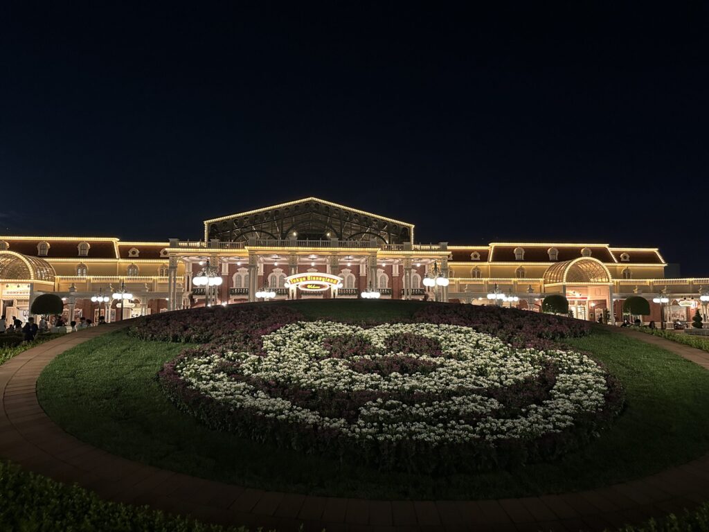 夜の東京ディズニーランドのエントランスと花で描かれたミッキーシェイプ